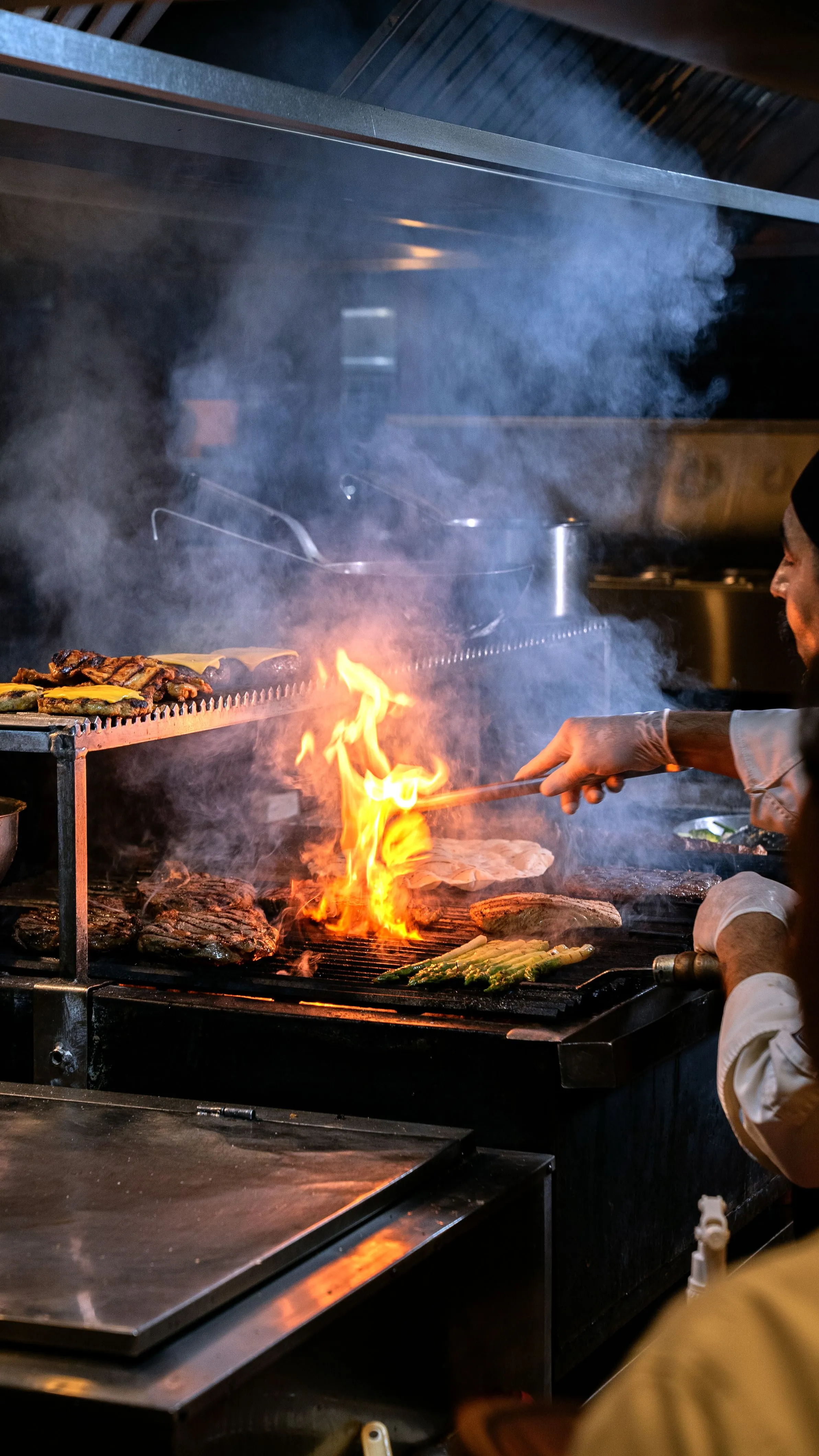 Parrillero atizando la brasa de leña en la cocina de Asador Artebe