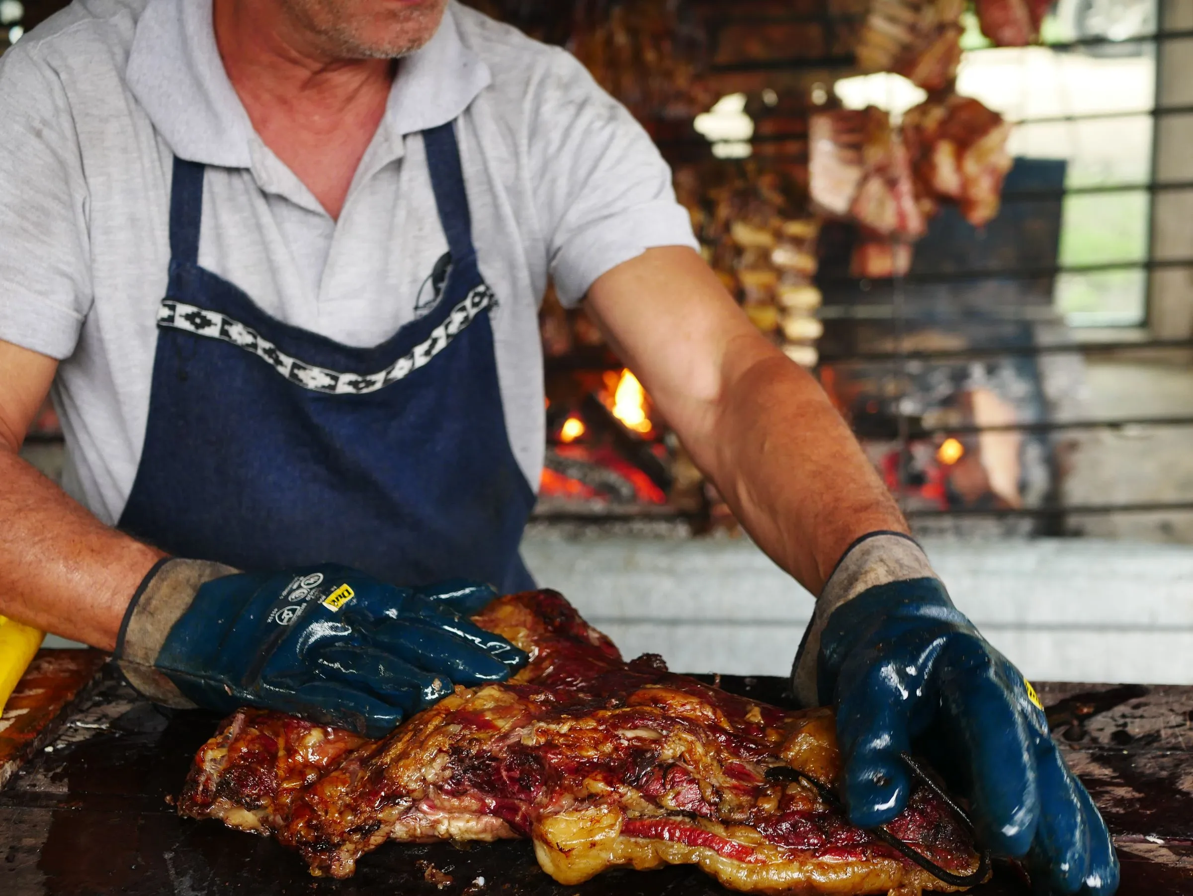 Manos del parrillero con delantal, preparando carnes maduradas